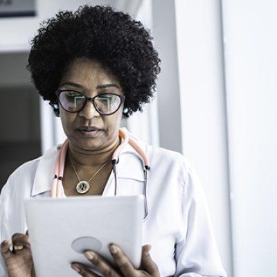 Mature female doctor using digital tablet at medical office