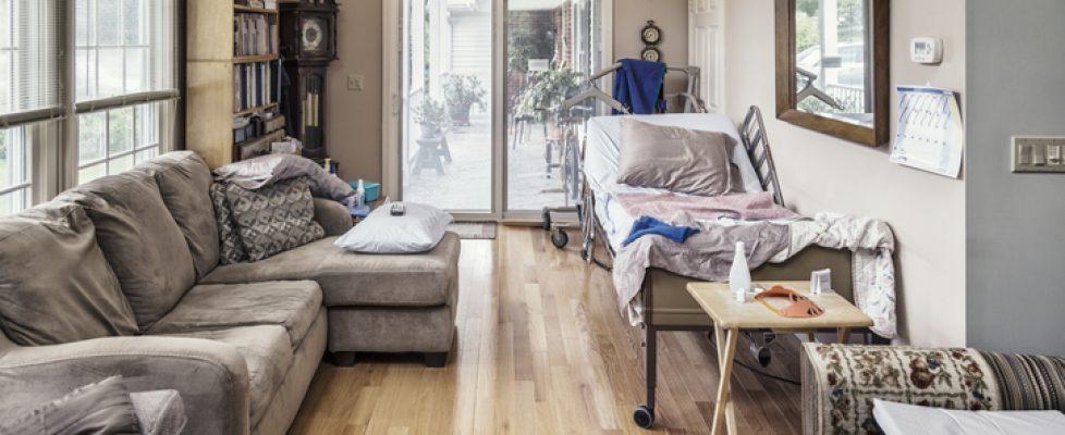 Raised Hospital Bed In Cluttered Private Residence Living Room